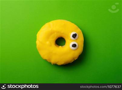 round yellow banana donut on a green background, flat lay