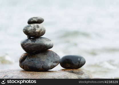 Rounded stones are set-up to pile, focus on stones, sea on the background.