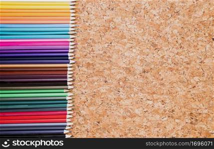 row color pencils cork background top view