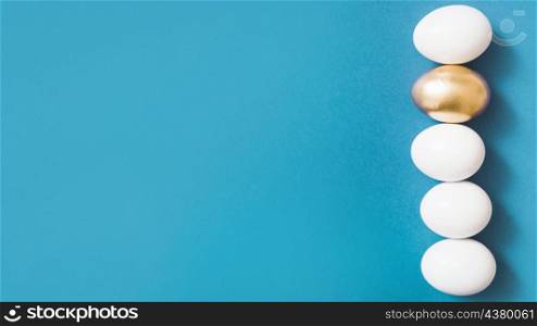 row common eggs with one golden egg blue background