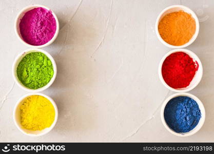 row holi color powder white bowls textured backdrop