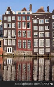 Row houses on a canal with reflections on water in Amsterdam, Holland, Netherlands.