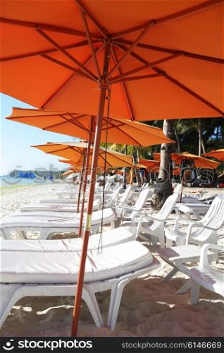 Row of beach umbrellas. Row of beach umbrellas and chaise lounge in a beach resort