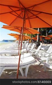 Row of beach umbrellas. Row of beach umbrellas and chaise lounge in a beach resort