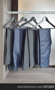 row of black pants hangs in wardrobe at home