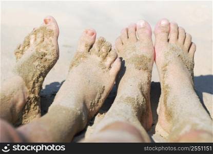 Row of children&acute;s feet on a beach covered in sand