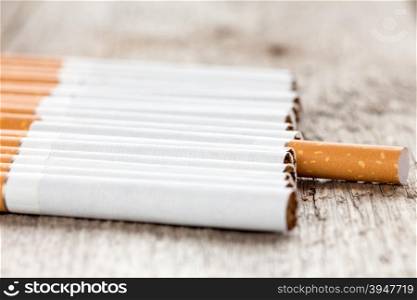 Row of cigarettes on wooden background with selective focus