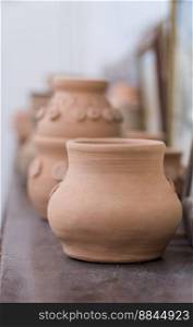 row of clay pots on the shelf, blurred background. children&rsquo;s crafts. clay art pots