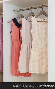 row of colorful dress hanging on coat hanger in white wardrobe