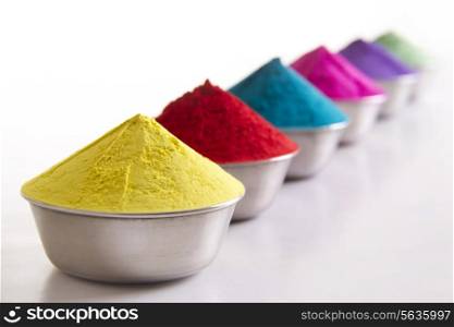 Row of colorful Holi powder in containers over white background