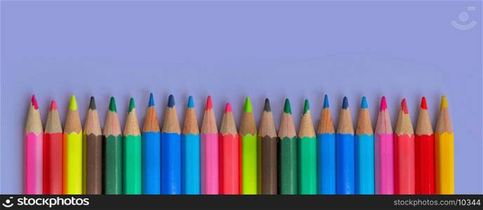 row of colorful wooden pencil on purple background