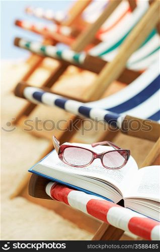 Row of deck chairs on beach book with sunglasses in foreground