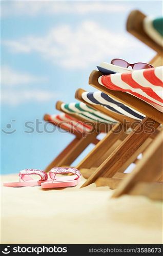Row of deck chairs on beach focus on flip-flops on ground