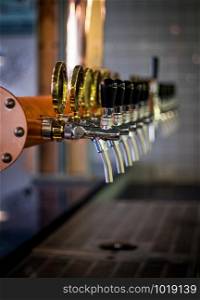 Row of draft beer tab on the top of counter bar in closeup view, time of celebration, selective focus.