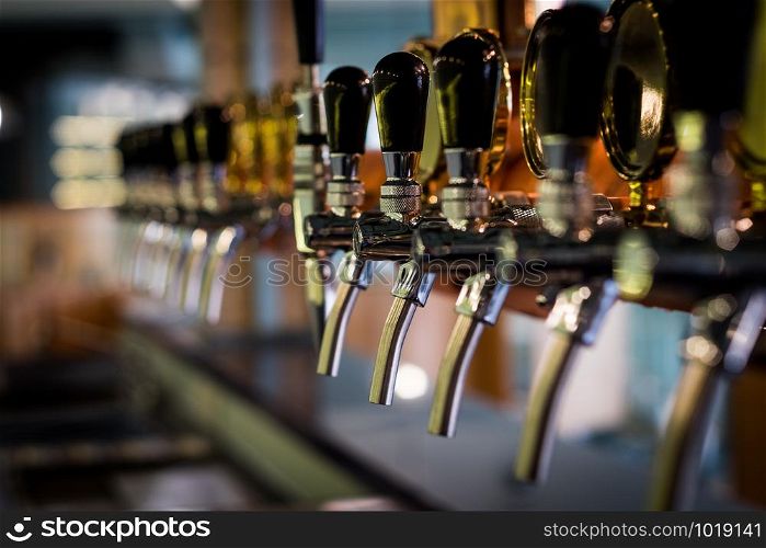 Row of draft beer tab on the top of counter bar in closeup view, time of celebration, selective focus.