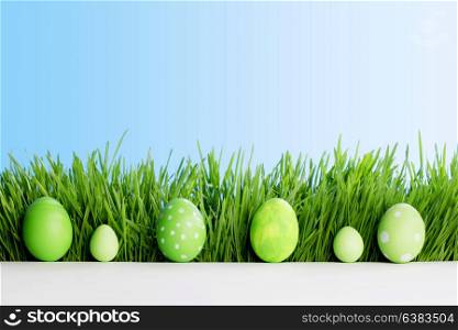 Row of Easter Eggs in fresh green grass over blue sky background