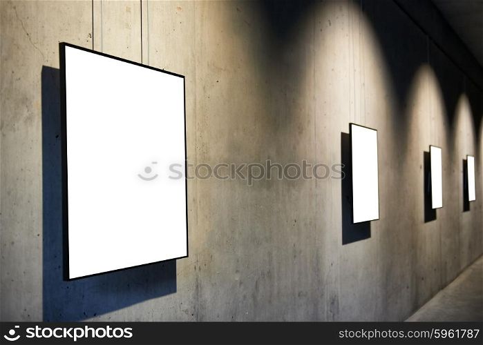 Row of empty black frames on concrete wall in the gallery isolated on white