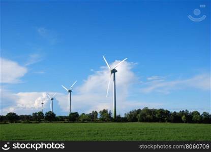 Row of four windmills in green surroundings in summer