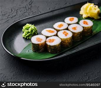 Row of fresh maki sushi rolls on black plate