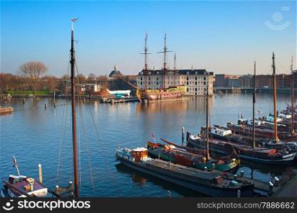 Row of houseboats on the Amstel river in Amsterdam, Netherlands. National Maritime Museum on the background