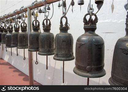 Row of large old traditional religious bells hanging in buddhist temple in Bangkok, Thailand