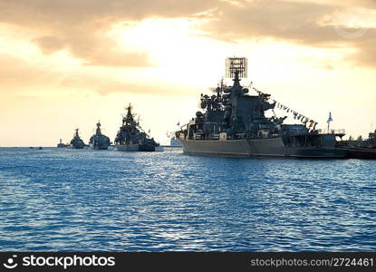 Row of military ships against marine sunset