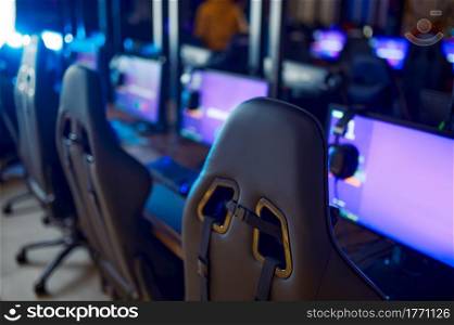 Row of monitors with headsets, gaming club interoir, nobody. Virtual entertainment, e-sport tournament, cybersport lifestyle. Internet cafe equipment. Row of monitors with headsets, gaming club, nobody