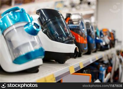 Row of new vacuum cleaners on the shelf in electronics store, nobody. Electric home appliances sale in supermarket. Vacuum cleaners in electronics store, nobody