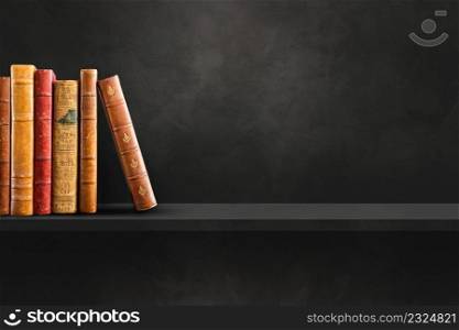 Row of old books on black shelf. Horizontal background scene. Row of old books on black shelf. Horizontal background