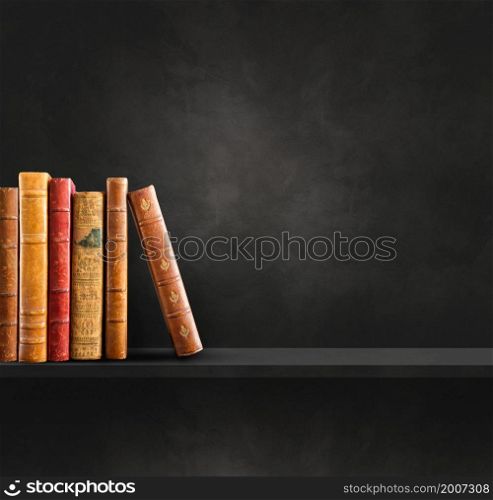 Row of old books on black shelf. Square scene background. Row of old books on black shelf. Square background