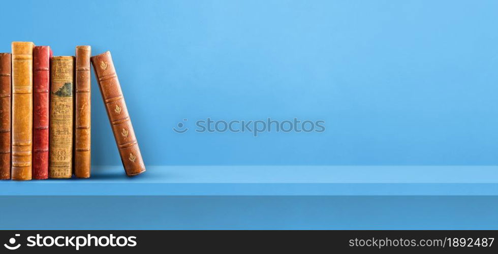 Row of old books on blue shelf. Horizontal background banner. Row of old books on blue shelf. Background banner