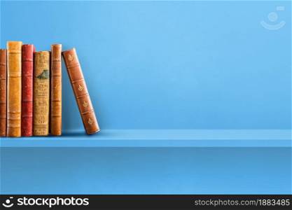 Row of old books on blue shelf. Horizontal background scene. Row of old books on blue shelf. Horizontal background