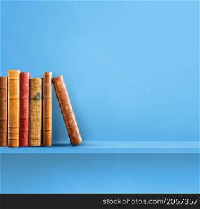 Row of old books on blue shelf. Square scene background. Row of old books on blue shelf. Square background