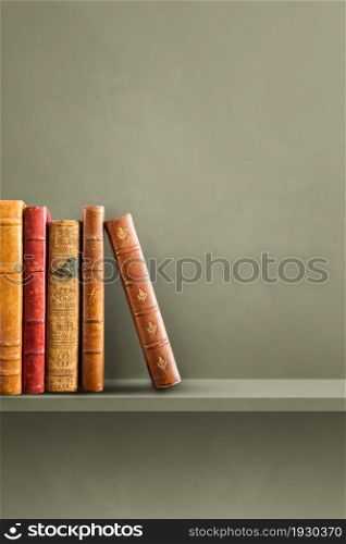 Row of old books on green shelf. Vertical background scene. Row of old books on green shelf. Vertical background