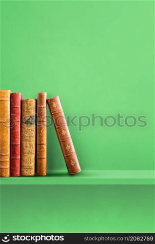 Row of old books on green shelf. Vertical background scene. Row of old books on green shelf. Vertical background