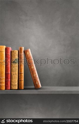 Row of old books on grey shelf. Vertical background scene. Row of old books on grey shelf. Vertical background