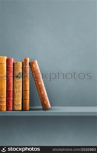 Row of old books on grey shelf. Vertical background scene. Row of old books on grey shelf. Vertical background