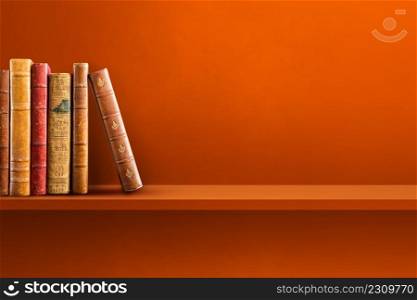 Row of old books on orange shelf. Horizontal background scene. Row of old books on orange shelf. Horizontal background