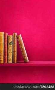 Row of old books on pink shelf. Vertical background scene. Row of old books on pink shelf. Vertical background