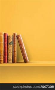 Row of old books on yellow shelf. Vertical background scene. Row of old books on yellow shelf. Vertical background