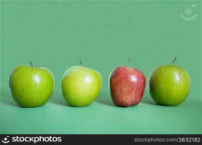Row of red and green apples over colored background