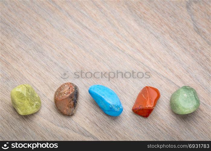 row of semiprecious colorful polished gemstones against grained wood with a copy space