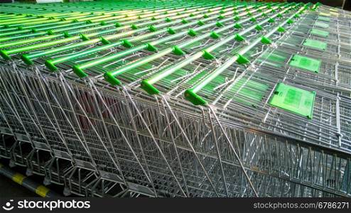Row of shopping carts with green handles in supermarket