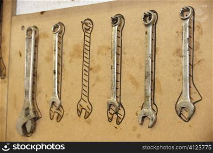 row of spanners hanging on a rack on a wall
