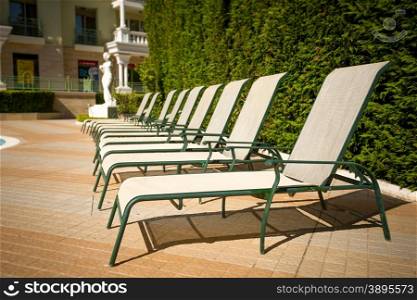 Row of sunbeds at poolside in luxurious hotel resort
