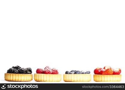 row of tartlets with sugar covered wild berries. row of tartlets with sugar covered wild berries on white background