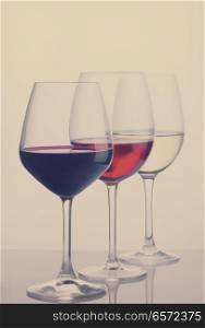 Row of three wine glasses with red, white and rose wine, retro toned. Set of glasses with wine