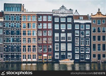Row of typical houses and boat on Amsterdam canal Damrak with reflection. Amsterdam, Netherlands. houses and boat on Amsterdam canal Damrak with reflection. Ams