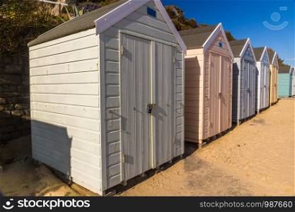 Row of UK beach huts in low sunlight, landscape