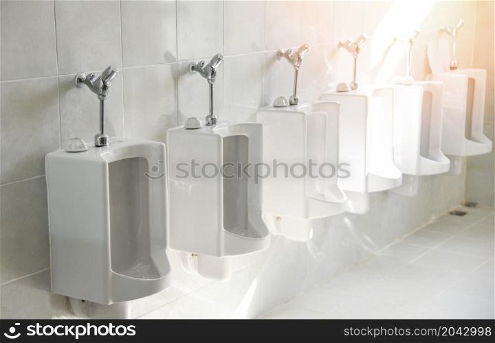 Row of urinal toilet blocks for man on tiled wall in public toilet